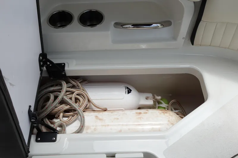 Slide: The Image of Storage compartment in a 2022 Stingray 231 DC boat with ropes and fenders. - 27
