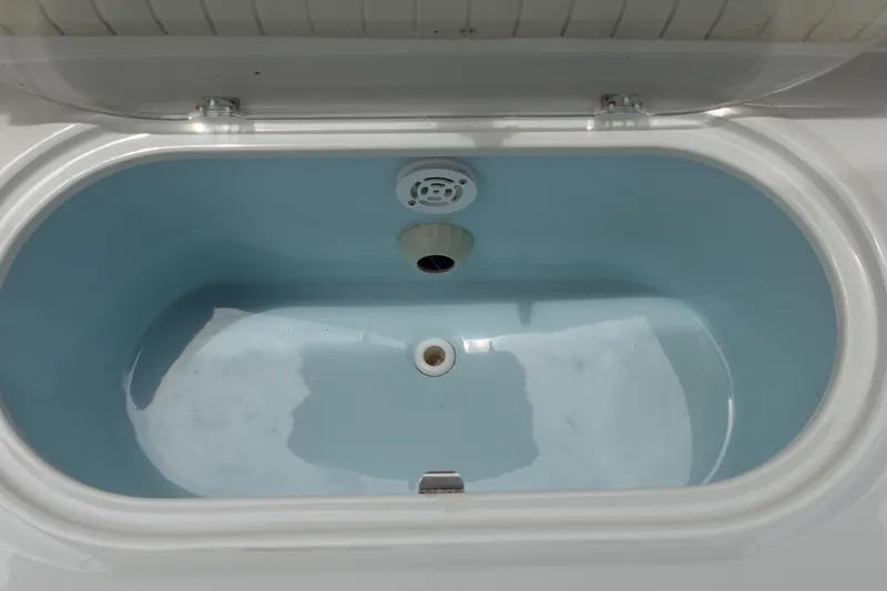 Slide: The Image of Livewell compartment in a 2022 Stingray 231 DC boat, featuring a blue interior. - 30