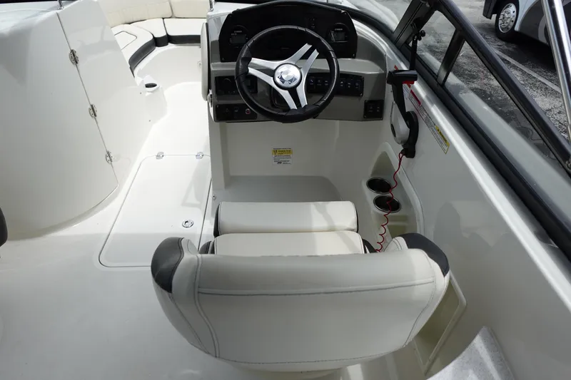 Slide: The Image of 2022 Stingray 231 DC boat interior with steering wheel and seating. - 37