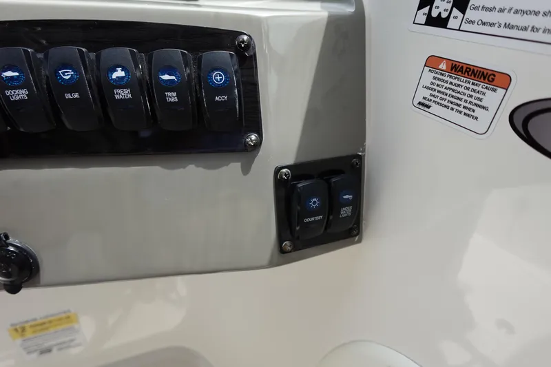 Slide: The Image of Control panel of 2022 Stingray 231 DC boat with labeled switches and warning labels. - 44