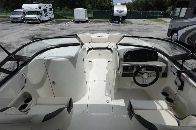 Slide: The Image of 2022 Stingray 231 DC boat interior with steering wheel, seating, and dashboard in a parking lot. - 48