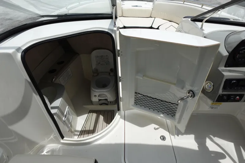 Slide: The Image of 2022 Stingray 231 DC boat interior with open door revealing compact bathroom. - 49