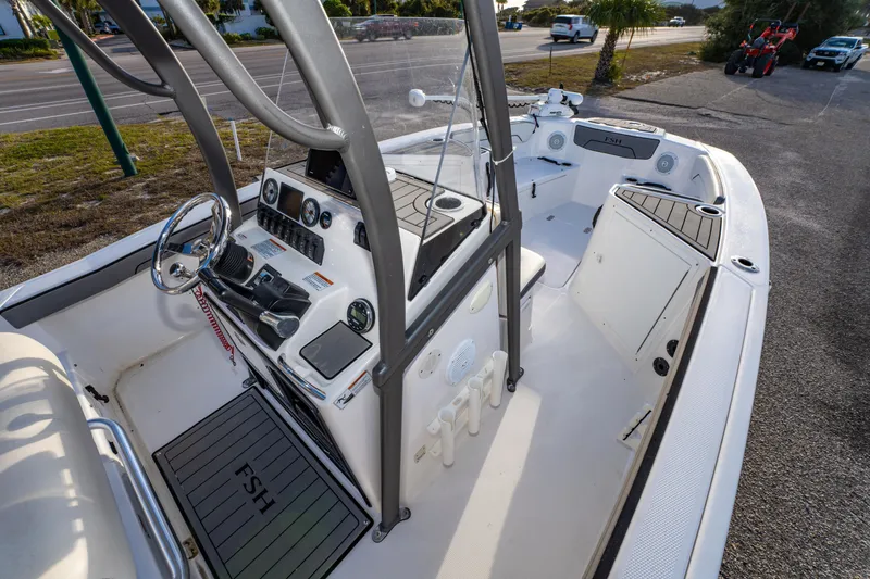 Slide: The Image of 2019 Yamaha Boats 210 FSH Sport interior with helm, controls, and seating area. - 21