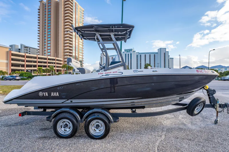 Slide: The Image of 2019 Yamaha Boats 210 FSH Sport on trailer, urban backdrop, clear sky. - 5
