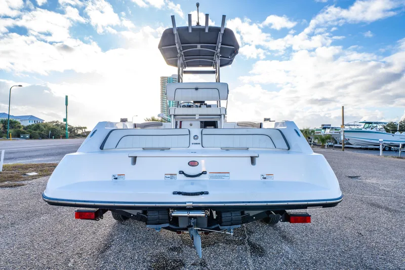 Slide: The Image of 2019 Yamaha Boats 210 FSH Sport, rear view, parked under a bright blue sky. - 7