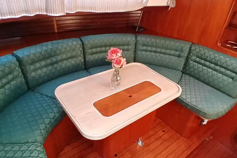 Slide: The Image of Interior of 1994 Beneteau Oceanis 44 CC with green seating and wooden table. - 11