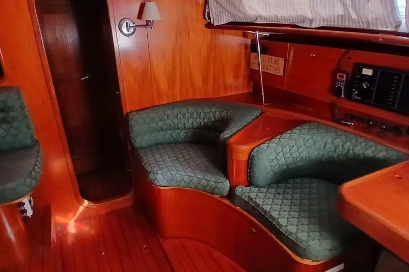 Slide: The Image of 1994 Beneteau Oceanis 44 CC interior with green cushioned seating and wooden finish. - 12