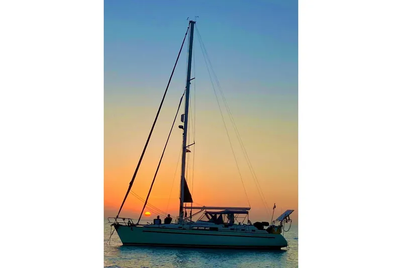 Slide: The Image of Sailboat Beneteau Oceanis 44 CC, 1994 model, silhouetted against a vibrant sunset. - 2