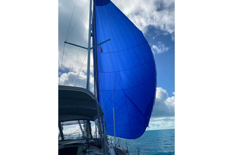 Slide: The Image of Sailing yacht Beneteau Oceanis 44 CC, 1994, with vibrant blue spinnaker against cloudy sky. - 4