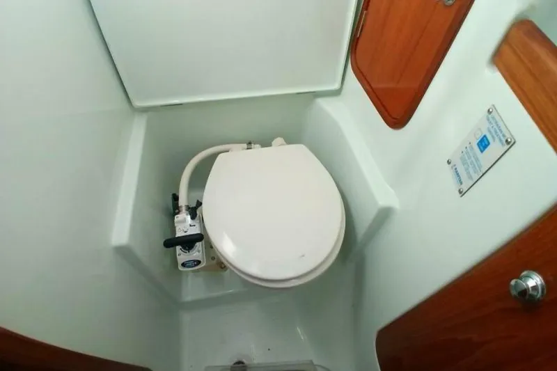Slide: The Image of 1994 Beneteau Oceanis 44 CC yacht bathroom with marine toilet and wooden accents. - 65