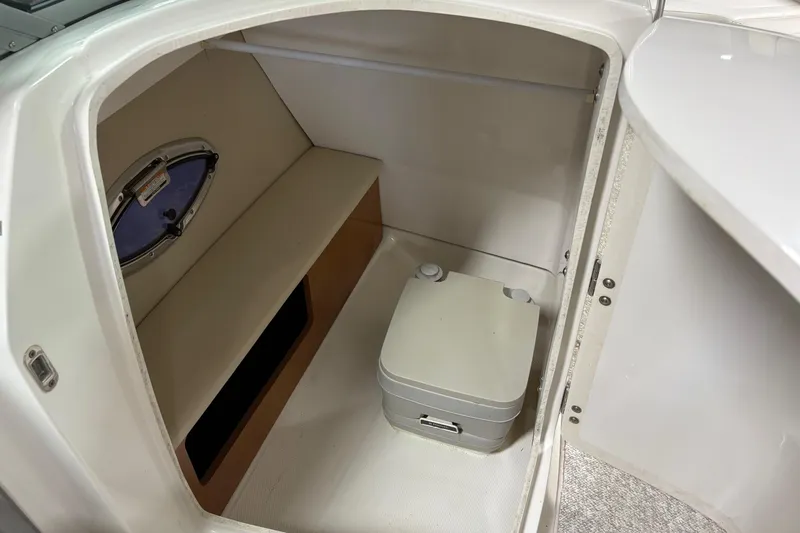 Slide: The Image of 2012 Chaparral 246 SSi boat interior with compact toilet and porthole window. - 15