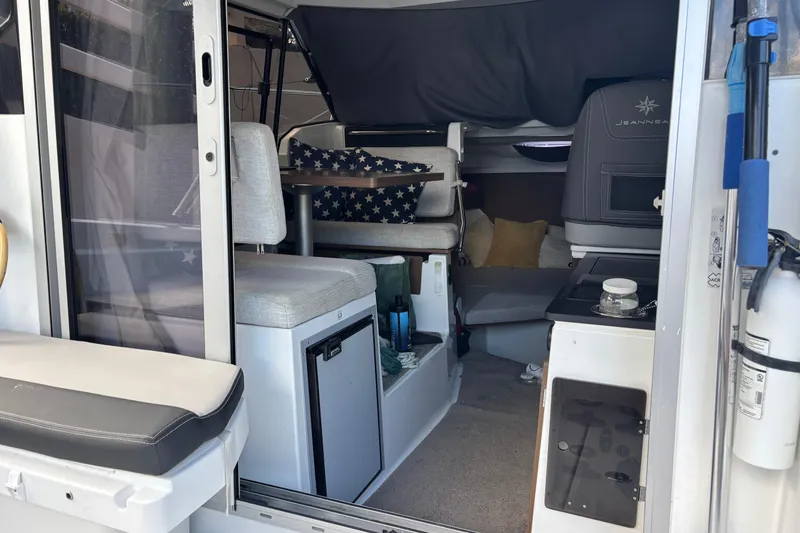 Slide: The Image of Interior of 2022 Jeanneau NC 795 Series 2 boat, featuring seating and compact kitchen area. - 2