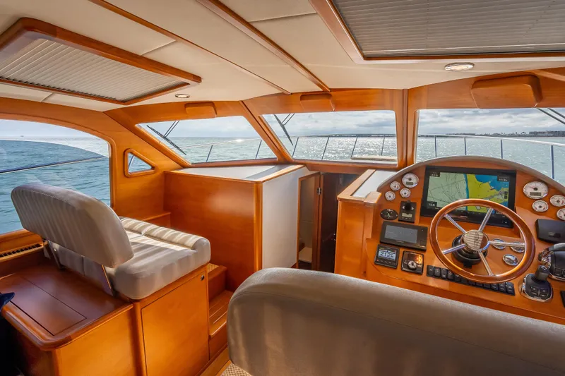 Slide: The Image of 2018 Palm Beach Motor Yachts PB50 helm with navigation system, luxurious wood finish, and ocean view. - 16