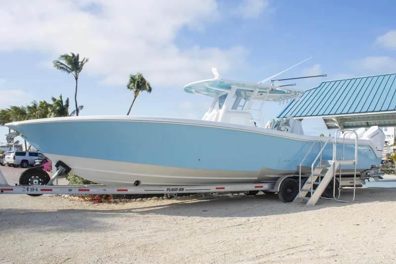 The Image of 2026 Invincible 39 Open Fisherman boat on trailer, light blue hull, palm trees in background. - 0
