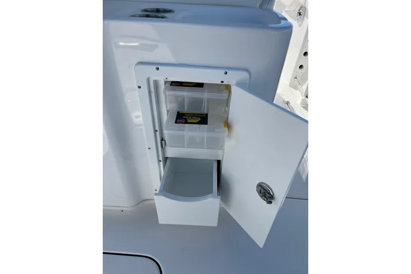 Slide: The Image of Tidewater 272 CC Adventure 2026 boat storage compartment with open door and tackle boxes. - 23