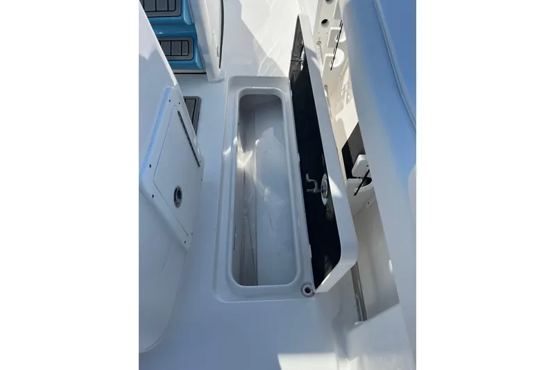 Slide: The Image of 2026 Tidewater 272 CC Adventure boat storage compartment, open lid, white interior. - 24