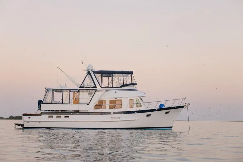 Slide: The Image of 2005 DeFever 49 Cockpit Motor Yacht on calm water at sunset. - 1