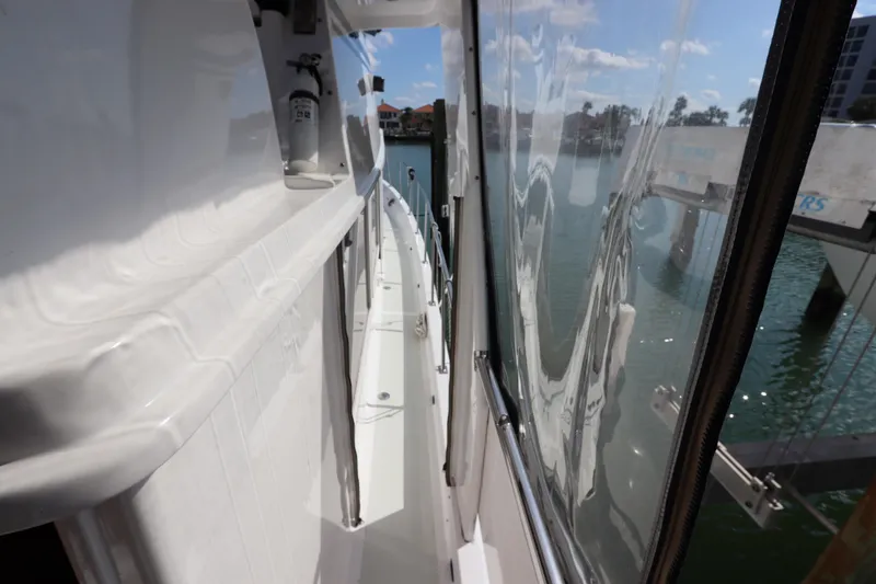 Slide: The Image of 2005 DeFever 49 Cockpit Motor Yacht side deck view with water reflection. - 15