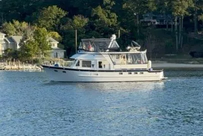 Slide: The Image of 2005 DeFever 49 Cockpit Motor Yacht cruising on a serene lake near a wooded shoreline. - 4