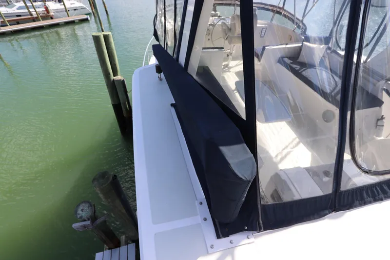 Slide: The Image of 2005 DeFever 49 Cockpit Motor Yacht docked, featuring spacious cockpit and clear enclosure. - 42