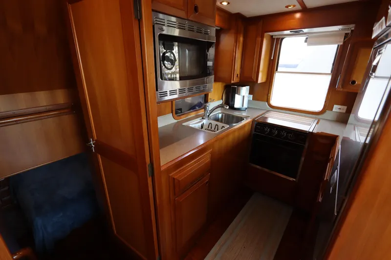 Slide: The Image of Luxurious 2005 DeFever 49 Cockpit Motor Yacht kitchen with wood cabinetry and modern appliances. - 49