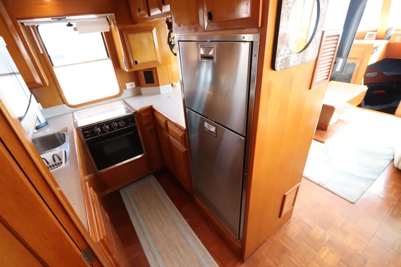Slide: The Image of 2005 DeFever 49 Cockpit Motor Yacht kitchen with stainless steel appliances and wooden cabinetry. - 52