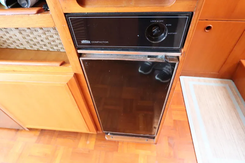 Slide: The Image of Built-in trash compactor on 2005 DeFever 49 Cockpit Motor Yacht, featuring wood cabinetry. - 58