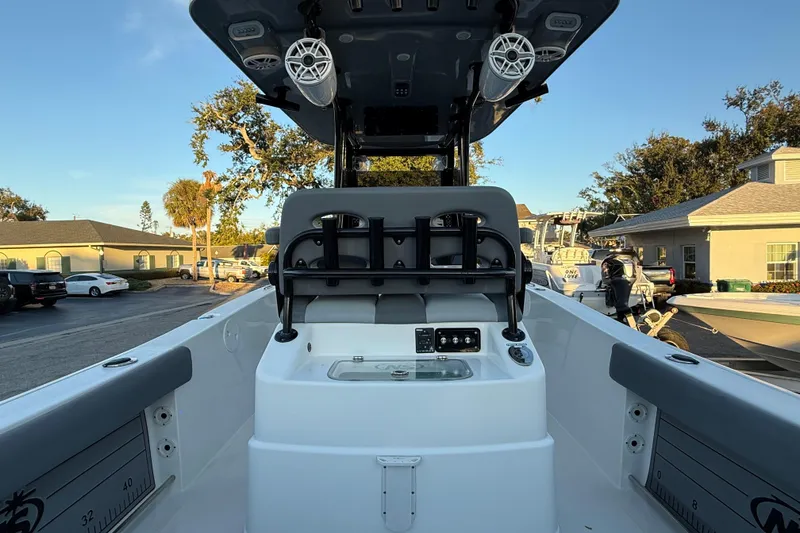 Slide: The Image of 2023 NauticStar 2602 Legacy boat interior with seating and speakers, parked outdoors. - 21