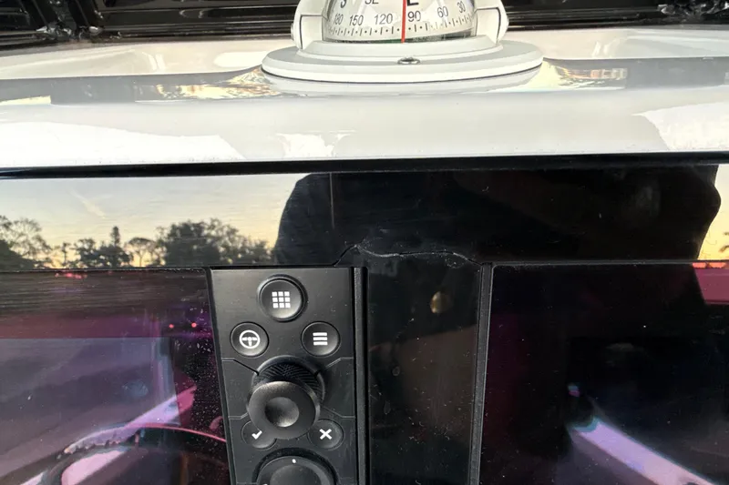 Slide: The Image of Control panel of 2023 NauticStar 2602 Legacy boat with compass and sunset reflection. - 42