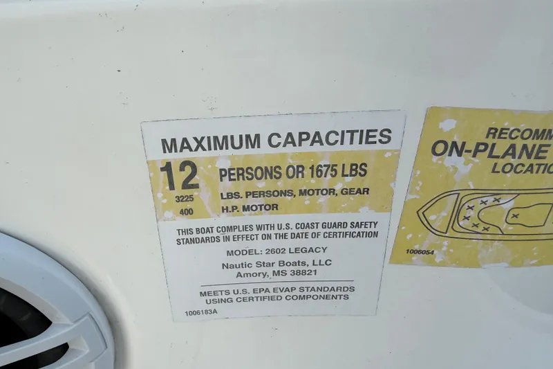 Slide: The Image of 2023 NauticStar 2602 Legacy capacity label, 12 persons or 1675 lbs, safety compliance. - 53