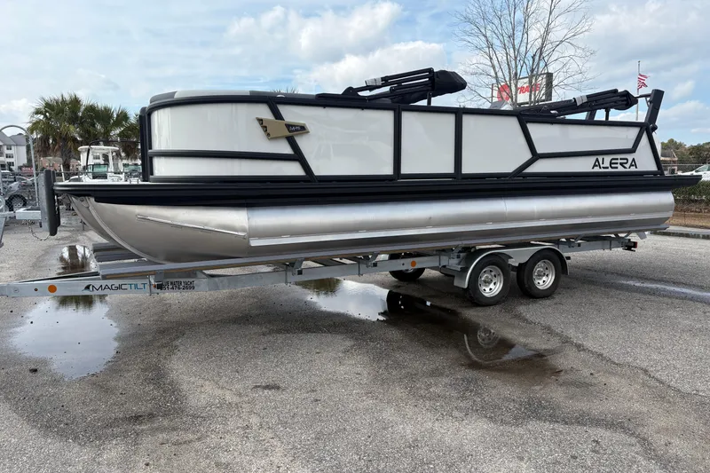 Slide: The Image of 2026 Alera M 25L pontoon boat on trailer, parked outdoors. - 0