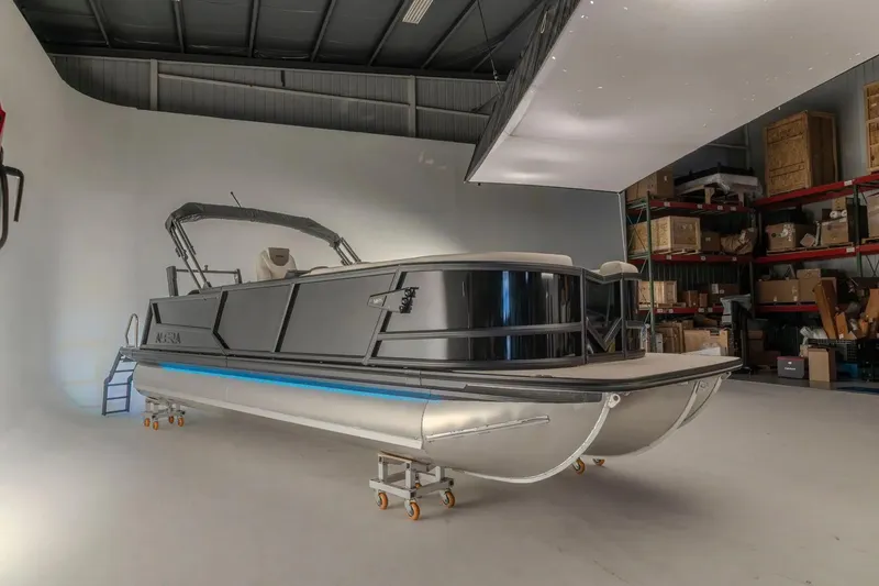 Slide: The Image of Alera M 25L 2026 pontoon boat with powerful outboard motor, parked on a trailer. - 2