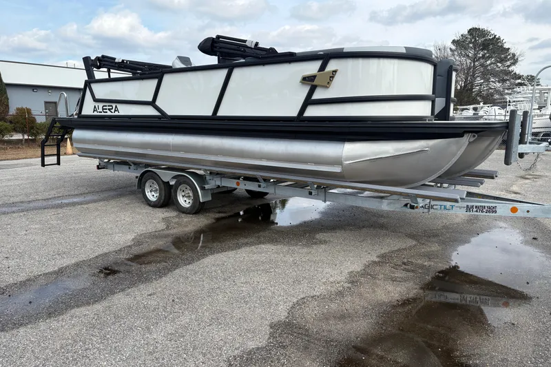 Slide: The Image of 2026 Alera M 25L pontoon boat on trailer, parked outdoors. - 5