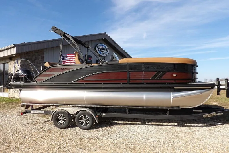 The Image of 2026 Bennington M L-Bench 22 ML pontoon boat on trailer, parked outside marine center. - 1