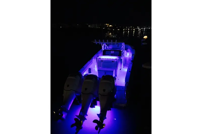 Slide: The Image of 2014 Nor-Tech 340 Sport Center Console boat illuminated with blue lights at night. - 2