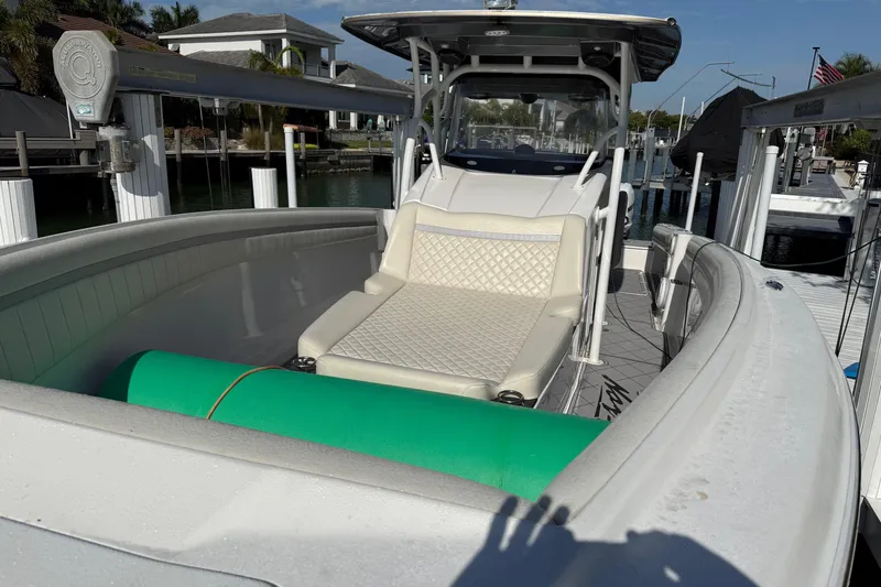Slide: The Image of 2014 Nor-Tech 340 Sport Center Console boat with cushioned seating and docked in a marina. - 4