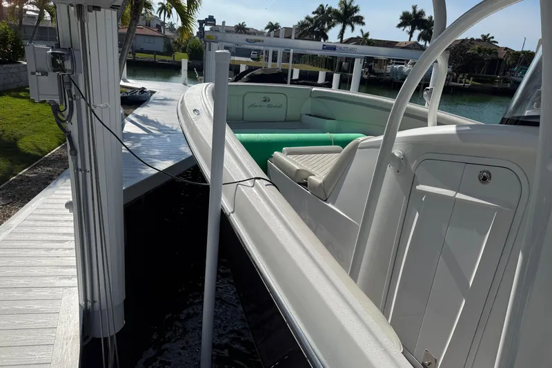 Slide: The Image of 2014 Nor-Tech 340 Sport Center Console docked by a waterfront with palm trees. - 5