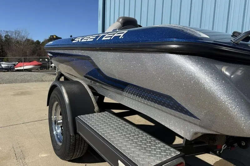 Slide: The Image of 2012 Skeeter TZX190 boat on trailer, metallic blue and silver finish, parked outdoors. - 4