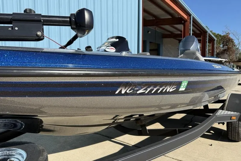 Slide: The Image of 2012 Skeeter TZX190 boat with blue and gray design, parked near a blue building. - 5