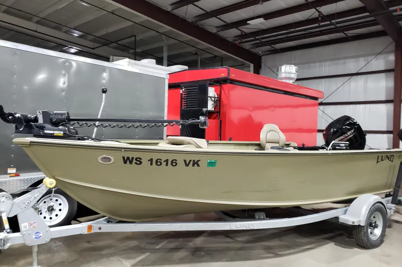 The Image of 2024 Lund 1675 Alaskan Tiller boat on trailer in warehouse setting. - 0