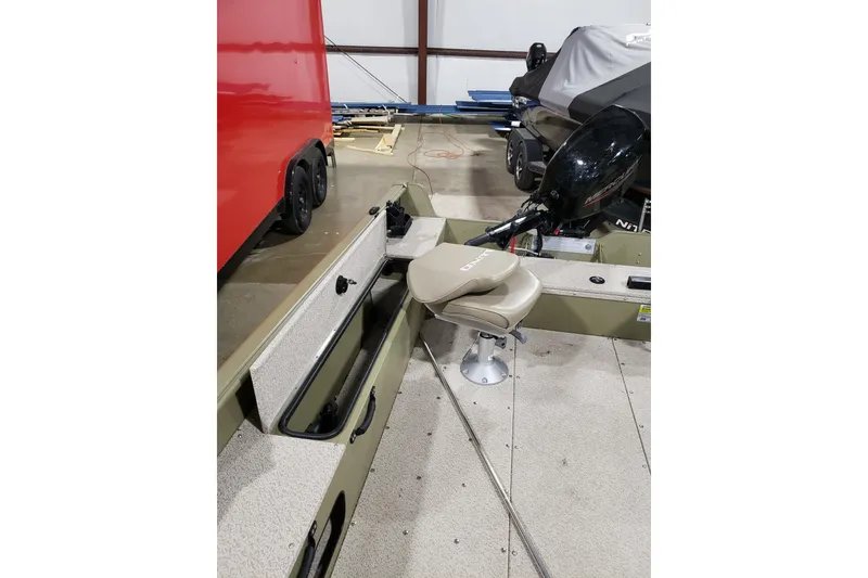 Slide: The Image of 2024 Lund 1675 Alaskan Tiller boat interior with seat and motor in a garage. - 14