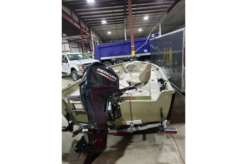 Slide: The Image of 2024 Lund 1675 Alaskan Tiller boat with Mercury outboard motor in a warehouse setting. - 3