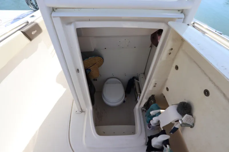 Slide: The Image of 2019 Robalo R242 Center Console boat interior with compact marine toilet. - 28
