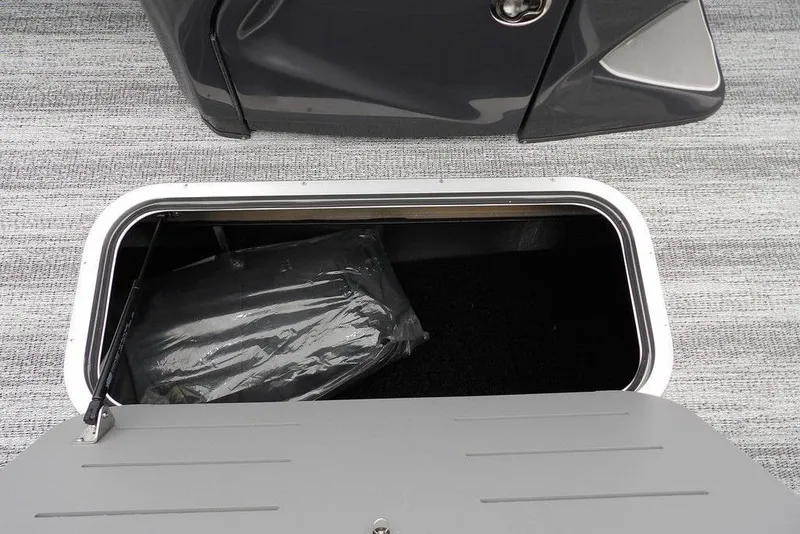 Slide: The Image of 2026 Bennington M L-Bench 22 ML storage compartment with open hatch on a textured floor. - 21