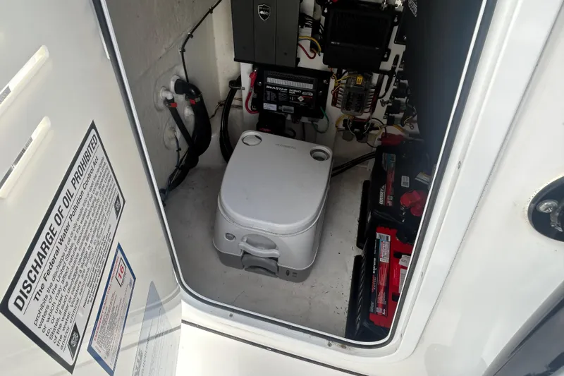 Slide: The Image of 2022 Crevalle 26 HBW boat interior with portable toilet and electrical components. - 17