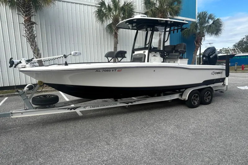 Slide: The Image of 2022 Crevalle 26 HBW boat on trailer, parked outdoors near palm trees. - 2