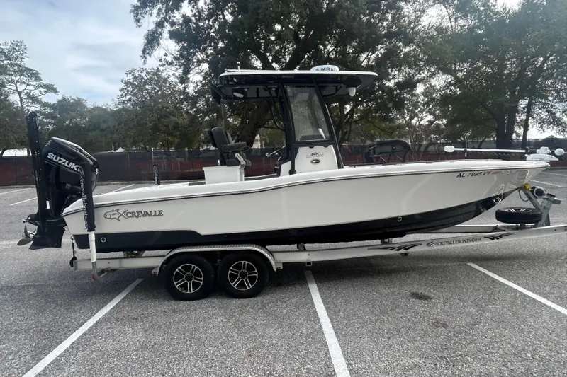 Slide: The Image of 2022 Crevalle 26 HBW boat on trailer, parked in a lot with trees in the background. - 7