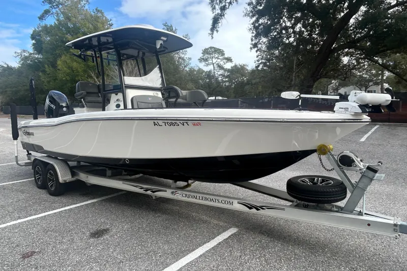 Slide: The Image of 2022 Crevalle 26 HBW boat on trailer in parking lot, surrounded by trees. - 8