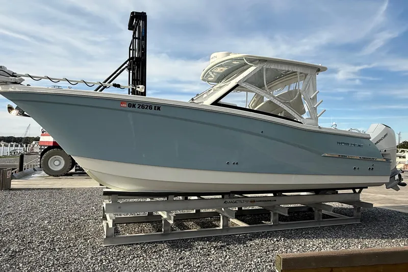 Slide: The Image of 2023 World Cat 280 DC-X boat on display, light blue hull, parked on gravel. - 10