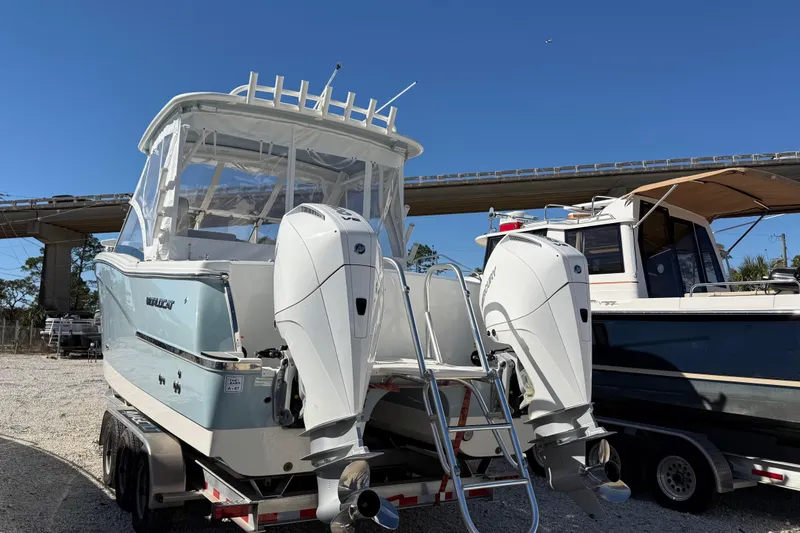 Slide: The Image of 2023 World Cat 280 DC-X boat with dual engines on a trailer, under a clear blue sky. - 24